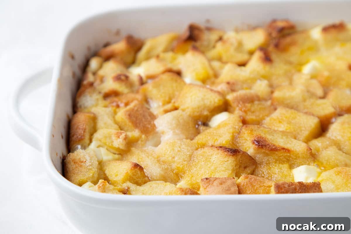 Baked Stuffed French Toast Casserole with Creamy Filling 3 white casserole dish filled with bread cubes and cream cheese to create stuffed french toast.