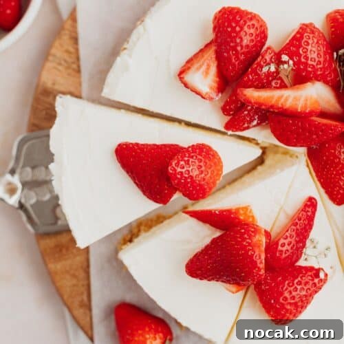 An overhead shot of a white cheesecake topped with sliced strawberries.