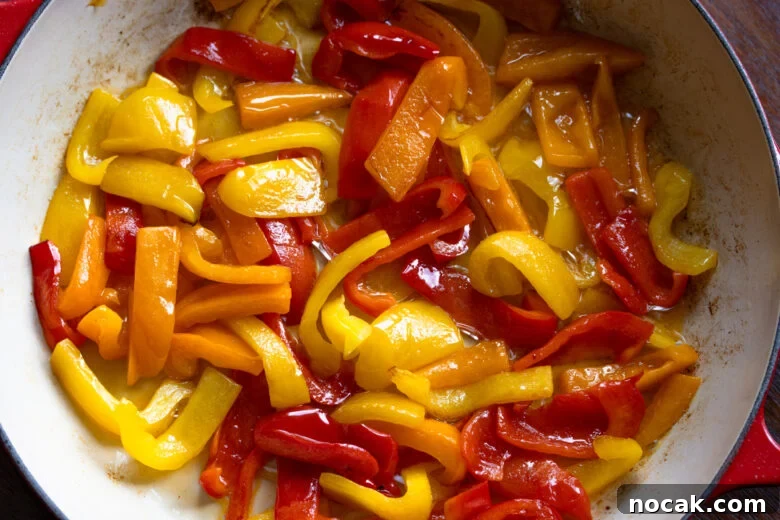 The bell peppers starting to soften during the cooking process.