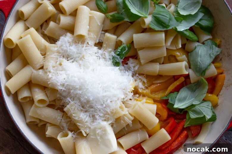 Cooked pasta added to the peppers alongside basil and grated Parmesan cheese. 