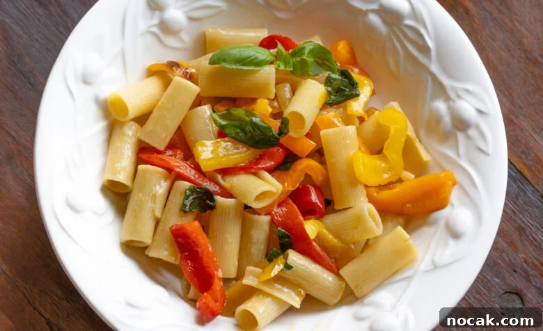 Roasted bell pepper sauce with garlic, basil and rigatoni pasta served in a white pasta dish. 