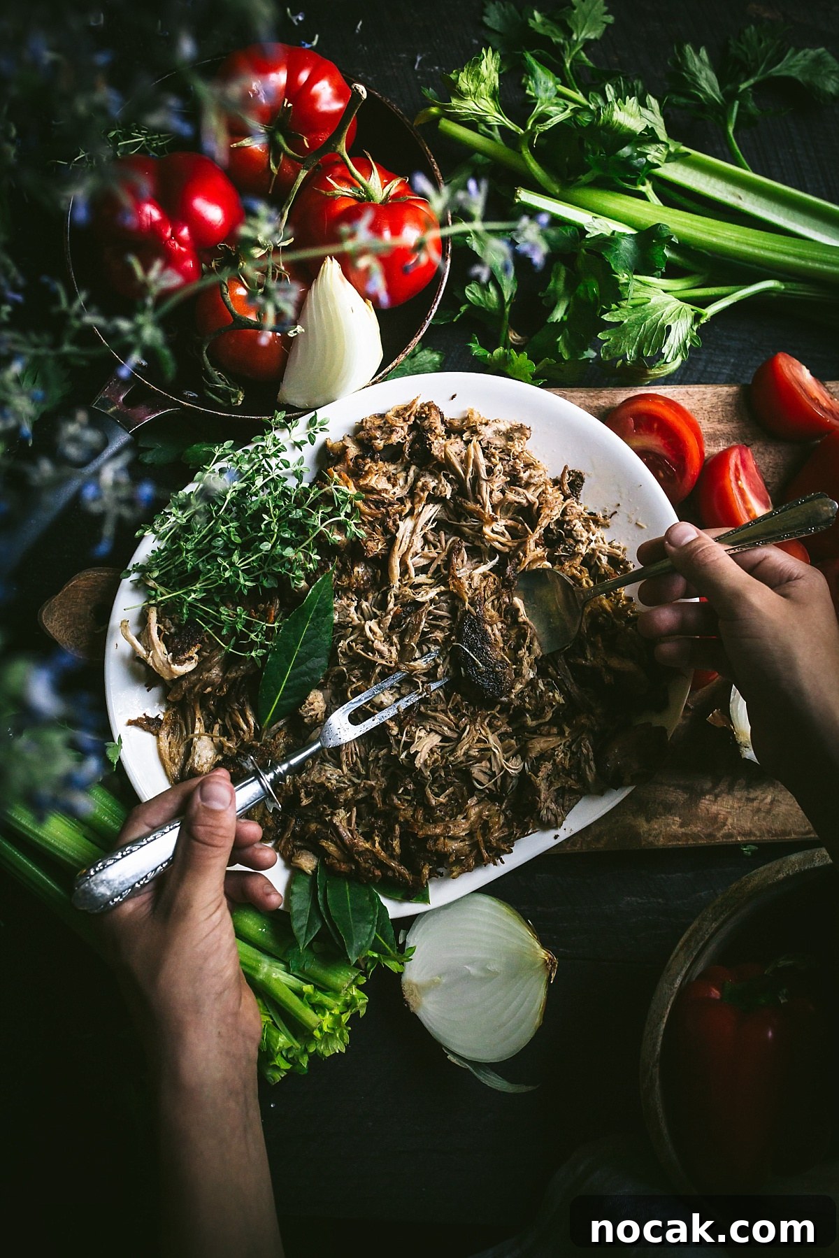 Paul Prudhomme’s Dutch Oven Jambalaya Recipe 7 overhead shot of hands shredded cajun spiced pulled pork surrounded by produce for Jambalaya