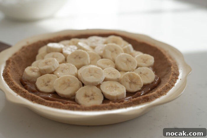 Classic Banoffee Pie Recipe: Creamy Toffee Banana Dessert 7 Banana slices are on top of graham cookie crusted pie dish