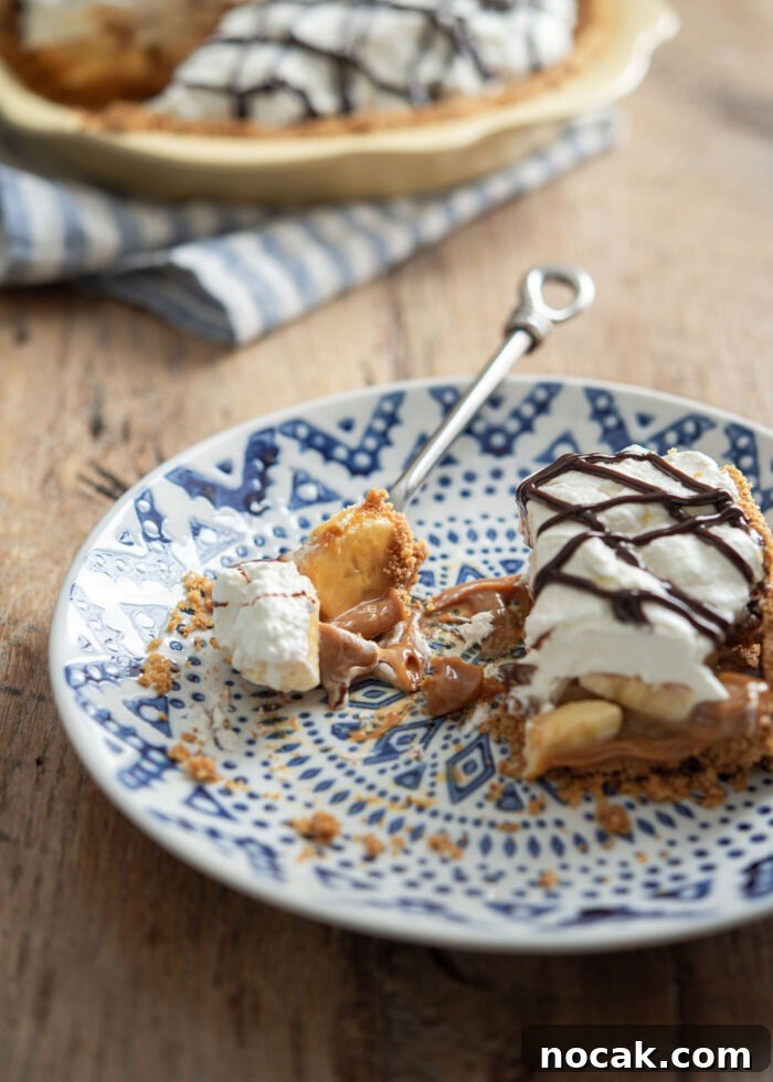 Classic Banoffee Pie Recipe: Creamy Toffee Banana Dessert 8 Serving a slice of banoffee pie topped with cream and chocolate syrup