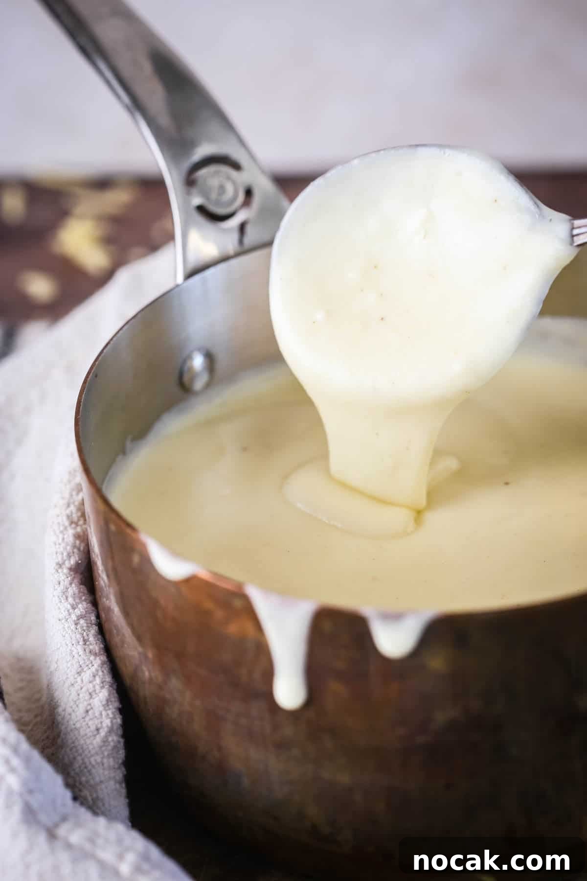 Creamy Gluten-Free Cheese Sauce Recipe for Dips & Pasta 9 Spooning gluten-free cheese sauce from saucepan showing velvety creamy texture.
