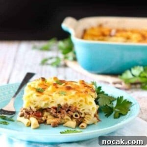 Classic Greek Pastitsio Recipe: Creamy Baked Pasta with Meat 3 Front view of plated pastitsio with casserole dish in background.