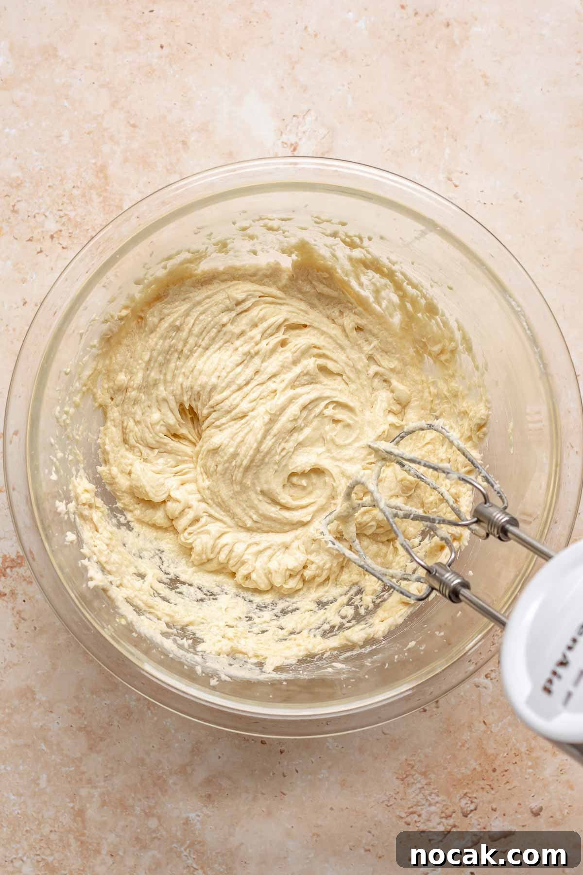 Cranberry Banana Bread Recipe with Zesty Orange Glaze 7 A hand mixer mixes banana bread batter in a bowl.
