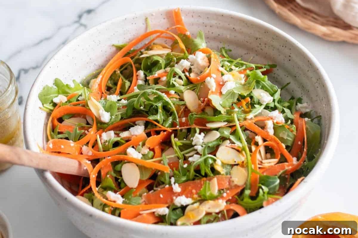 35 Easter Appetizers to Kick Off Your Holiday Feast 24 A fresh Easter appetizer salad with arugula, shaved carrots, crumbled cheese, and sliced almonds in a bowl with a wooden spoon.