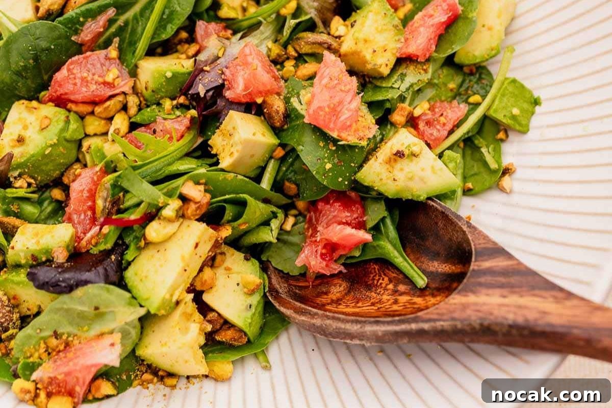 35 Easter Appetizers to Kick Off Your Holiday Feast 30 Close-up of a fresh avocado and grapefruit salad with greens and nuts, served as an Easter appetizer with a wooden spoon.