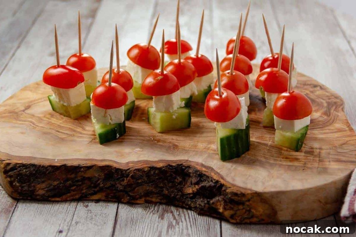35 Easter Appetizers to Kick Off Your Holiday Feast 31 An Easter appetizer platter of cherry tomato and cucumber appetizers with mozzarella and toothpick skewers, served on a wooden board.