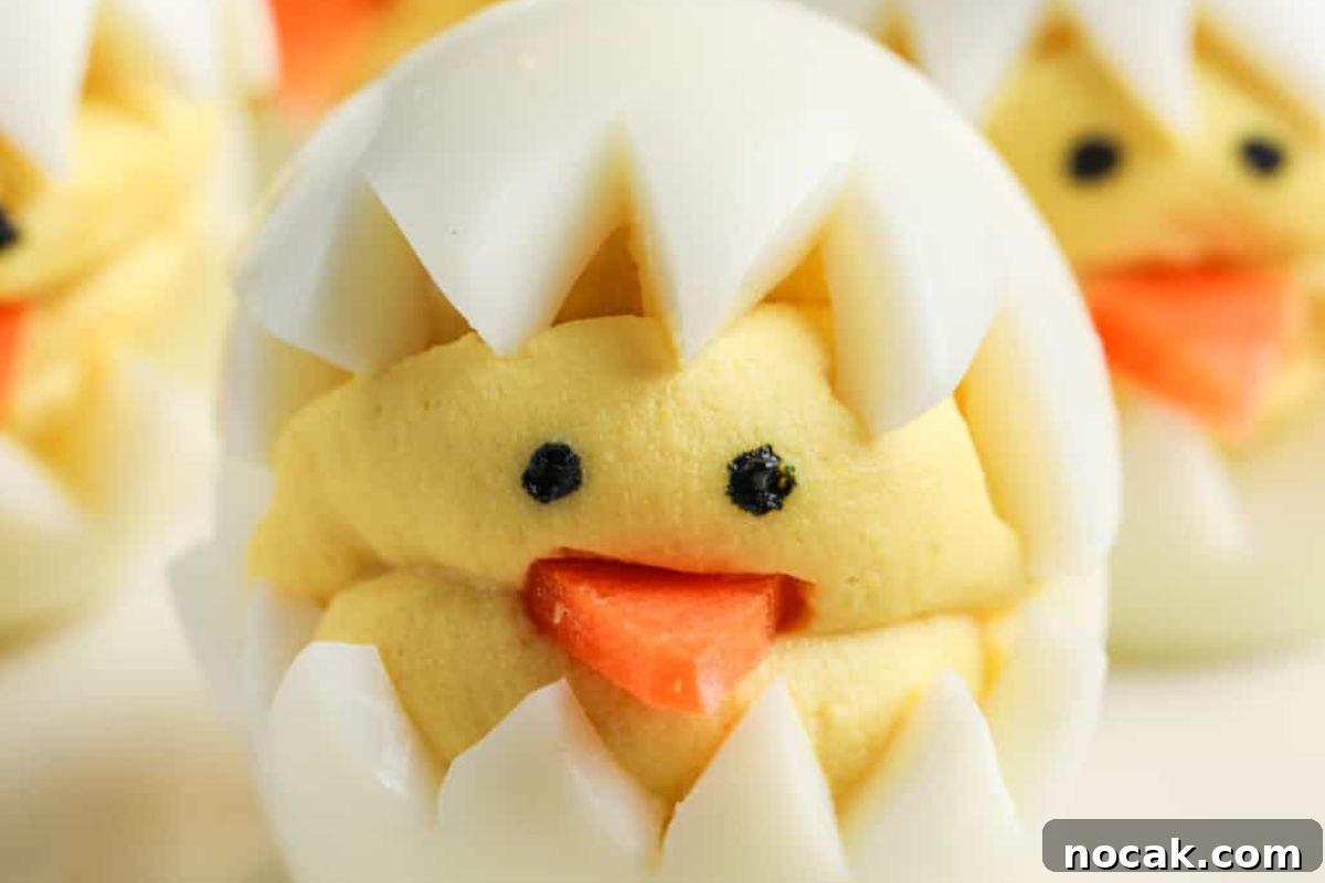 35 Easter Appetizers to Kick Off Your Holiday Feast 9 A close-up of a deviled egg creatively decorated to resemble a chick hatching from an egg, perfect as an Easter appetizer.