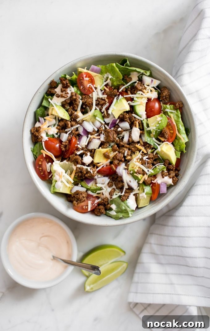 Low-Carb Chicken Taco Salad with Creamy Avocado Dressing 5 bowl of southwest taco salad beside small dressing bowl with a spoon and lime wedges