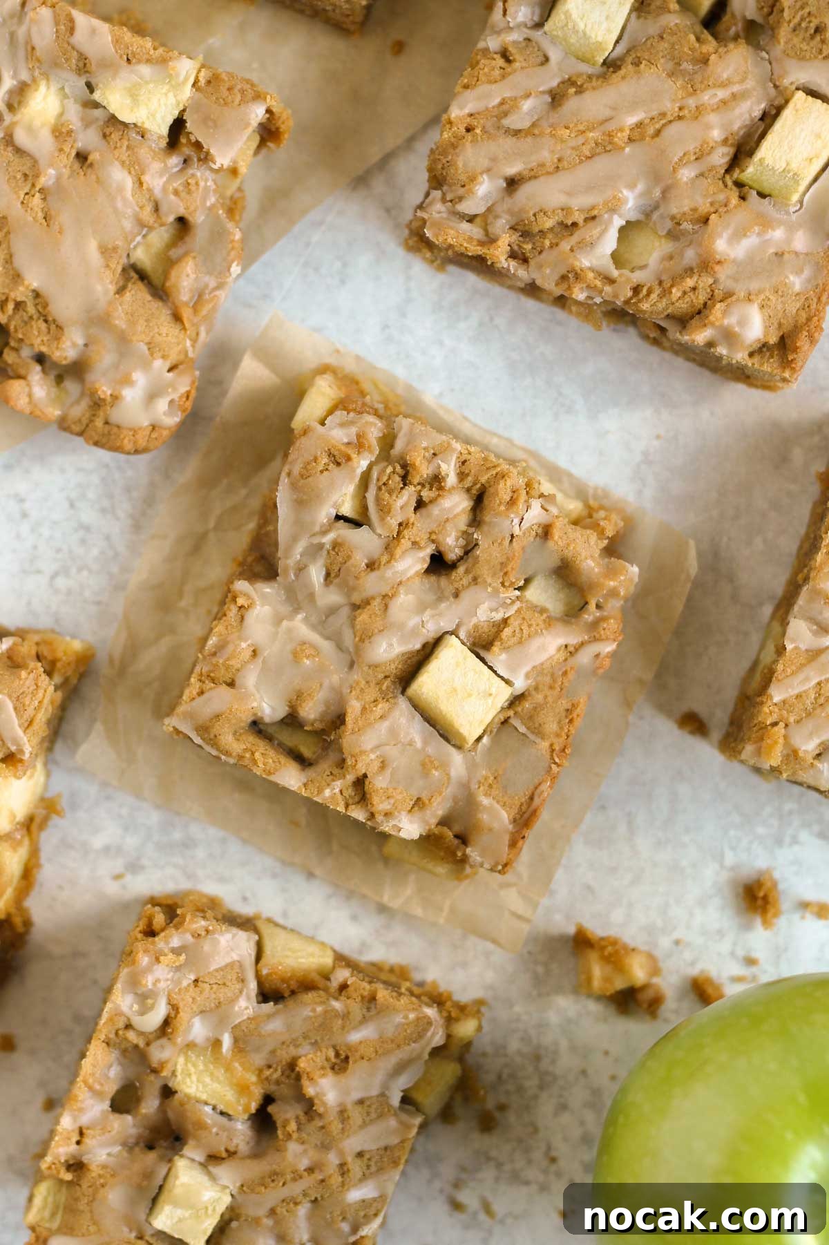 Cut-up apple blondie squares on a gray surface.