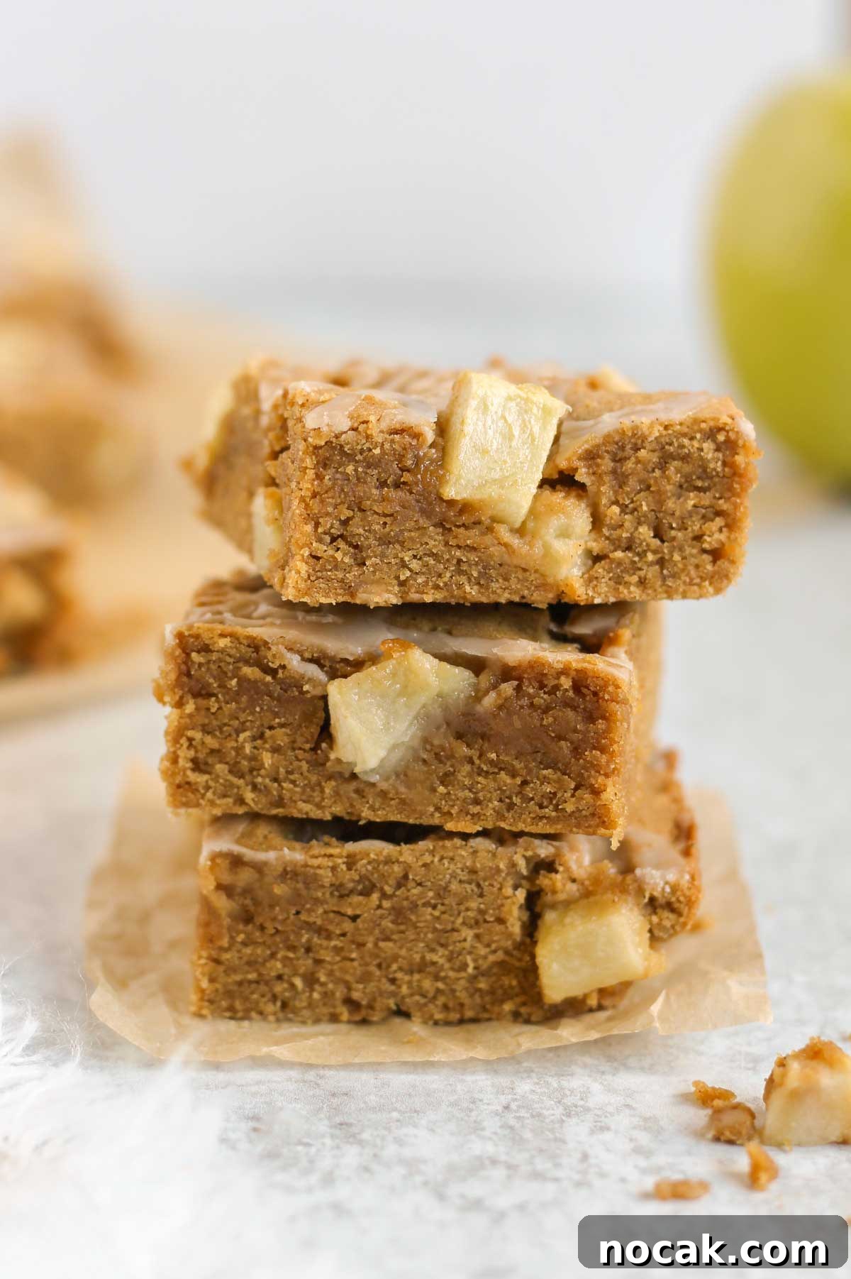 Apple blondie bars stacked 3 high with a green apple in the background.