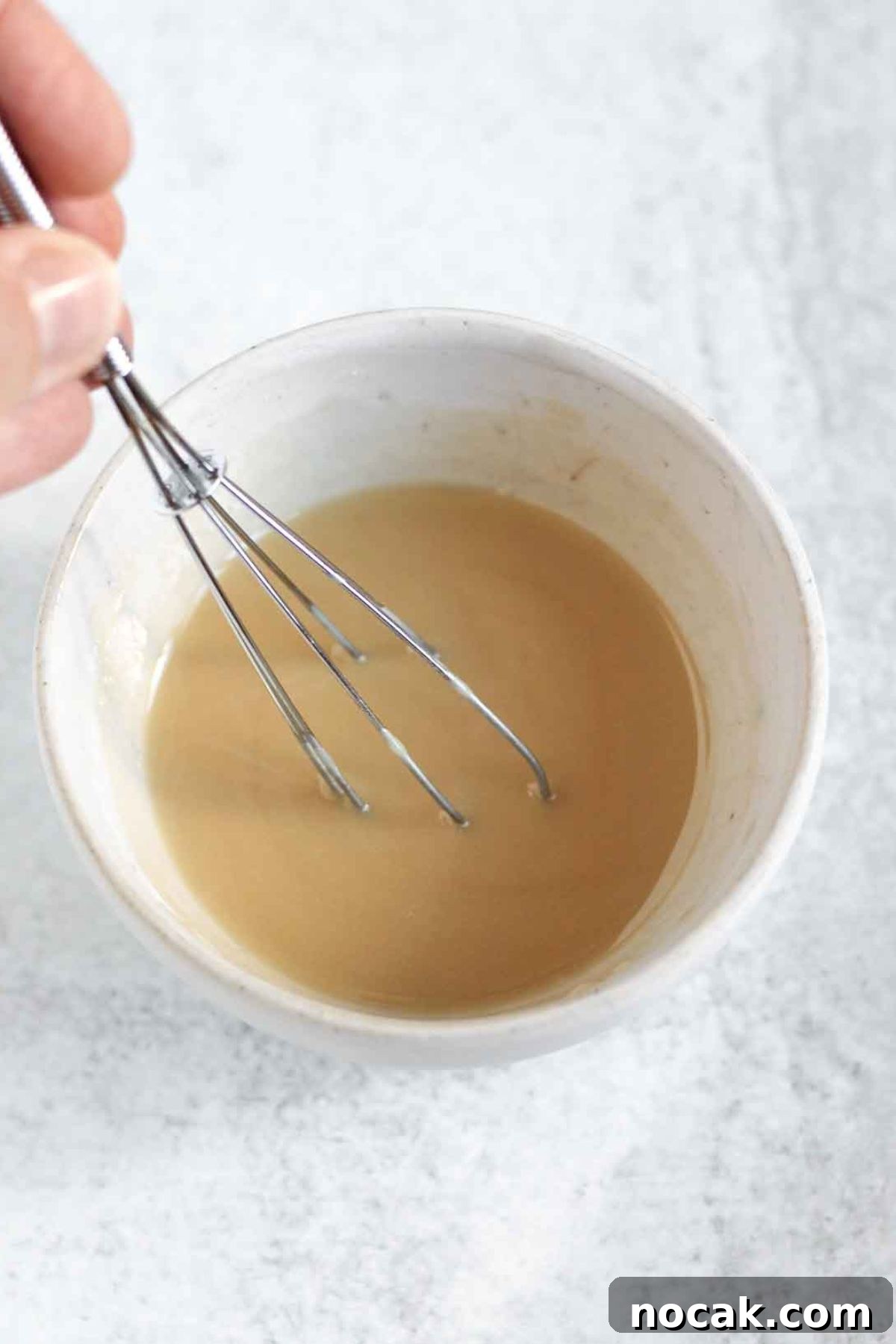 Small whisk whisking glaze in a small bowl.