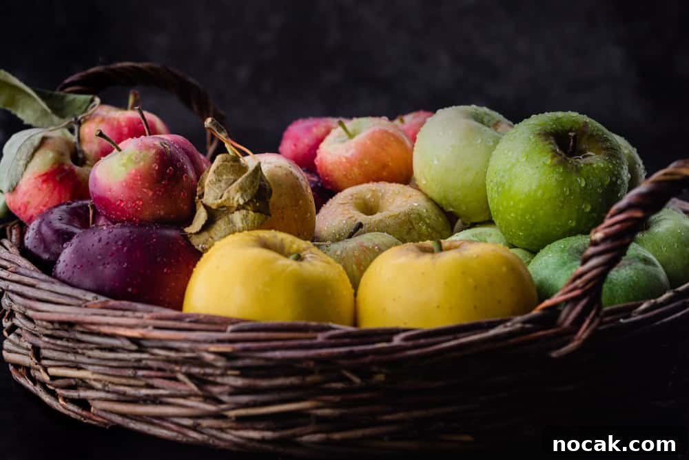 Red, pink, yellow, green and purple apples in a woven basket, side angle shot.