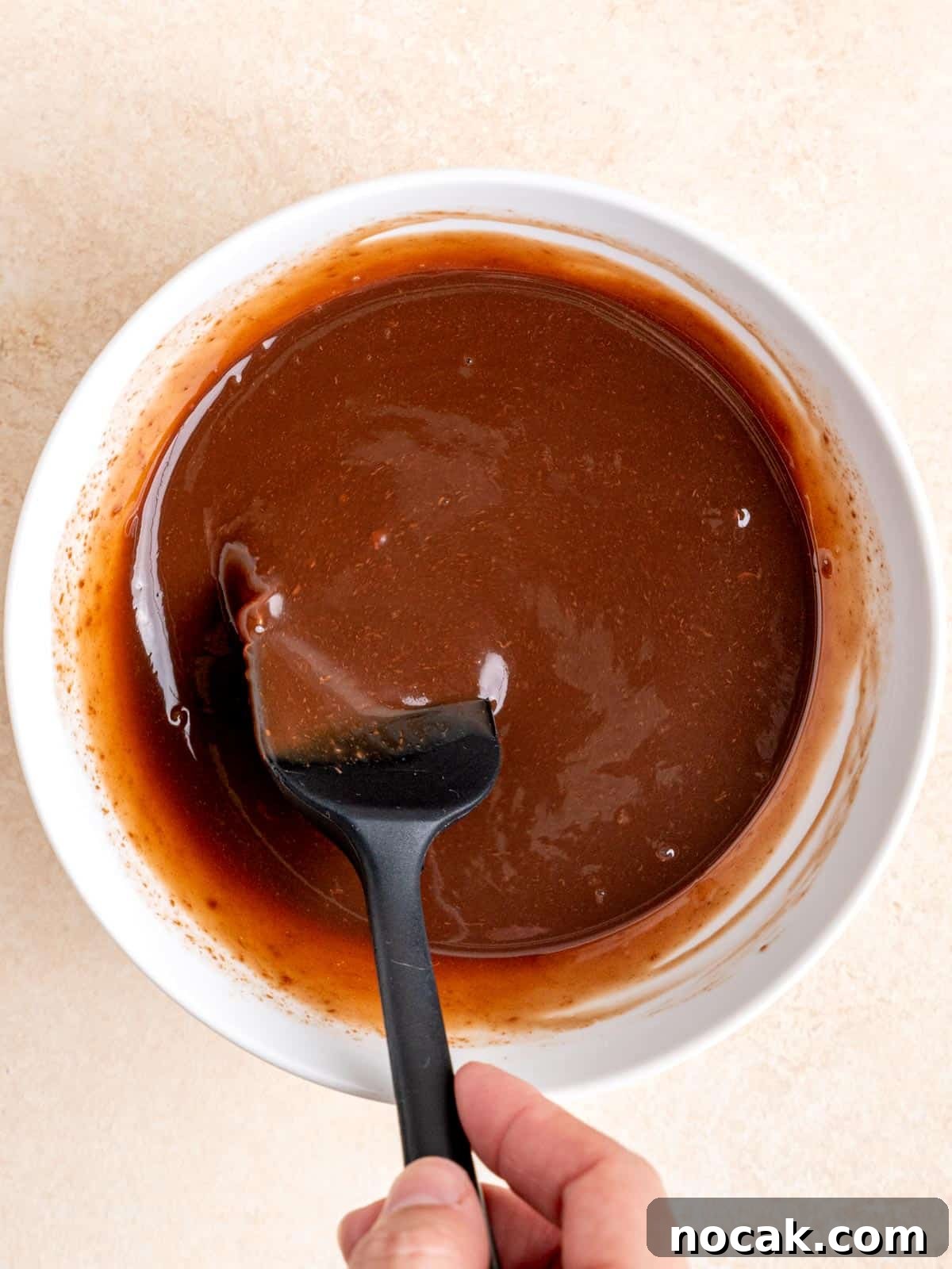 Chocolate Malted Crunch Ice Cream Recipe: Creamy Malted Chocolate with Crispy Crunch 7 Stirring a melted chocolate cream mixture in a bowl with a small rubber spatula.
