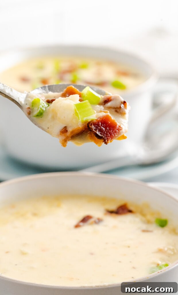 Creamy Instant Pot Cauliflower and Potato Soup Recipe 6 A spoonful of gluten-free cheesy cauliflower potato soup made in the instant pot hovering over white bowl.