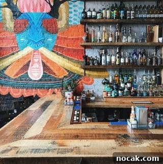 Top 5 Cocktail Recipes from 2017: Classic Drinks to Try 7 Half of a bar with bottles on shelves and a colorful painting on the wall