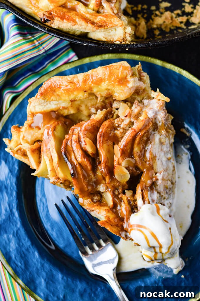 Rustic Apple Galette with Flaky Puff Pastry 5 A slice of apple galette sits on a blue plate with a scoop of ice cream melting on it. A blue striped napkin sits next to it.