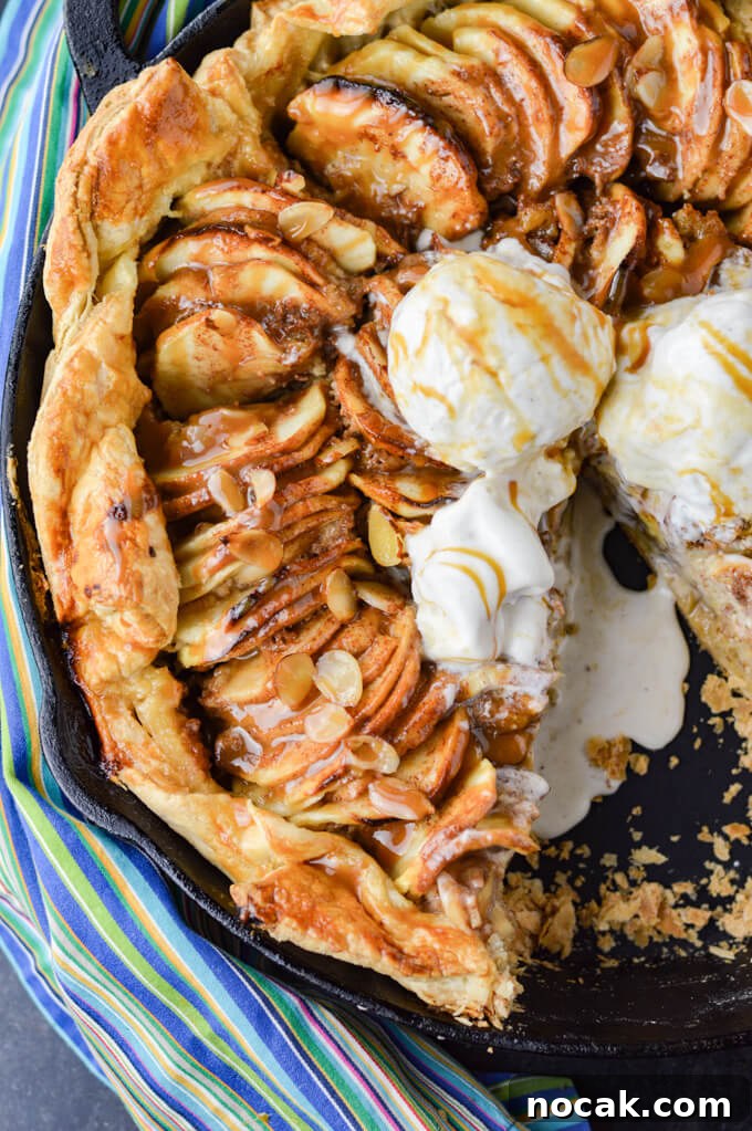 Rustic Apple Galette with Flaky Puff Pastry 6 Caramel Apple Galette with a puff pastry crust in a cast iron pan. A blue striped napkin sits next to it. Three scoops of ice cream sit on the apples. A slice is taken out of it and the ice cream is melting into the pan.