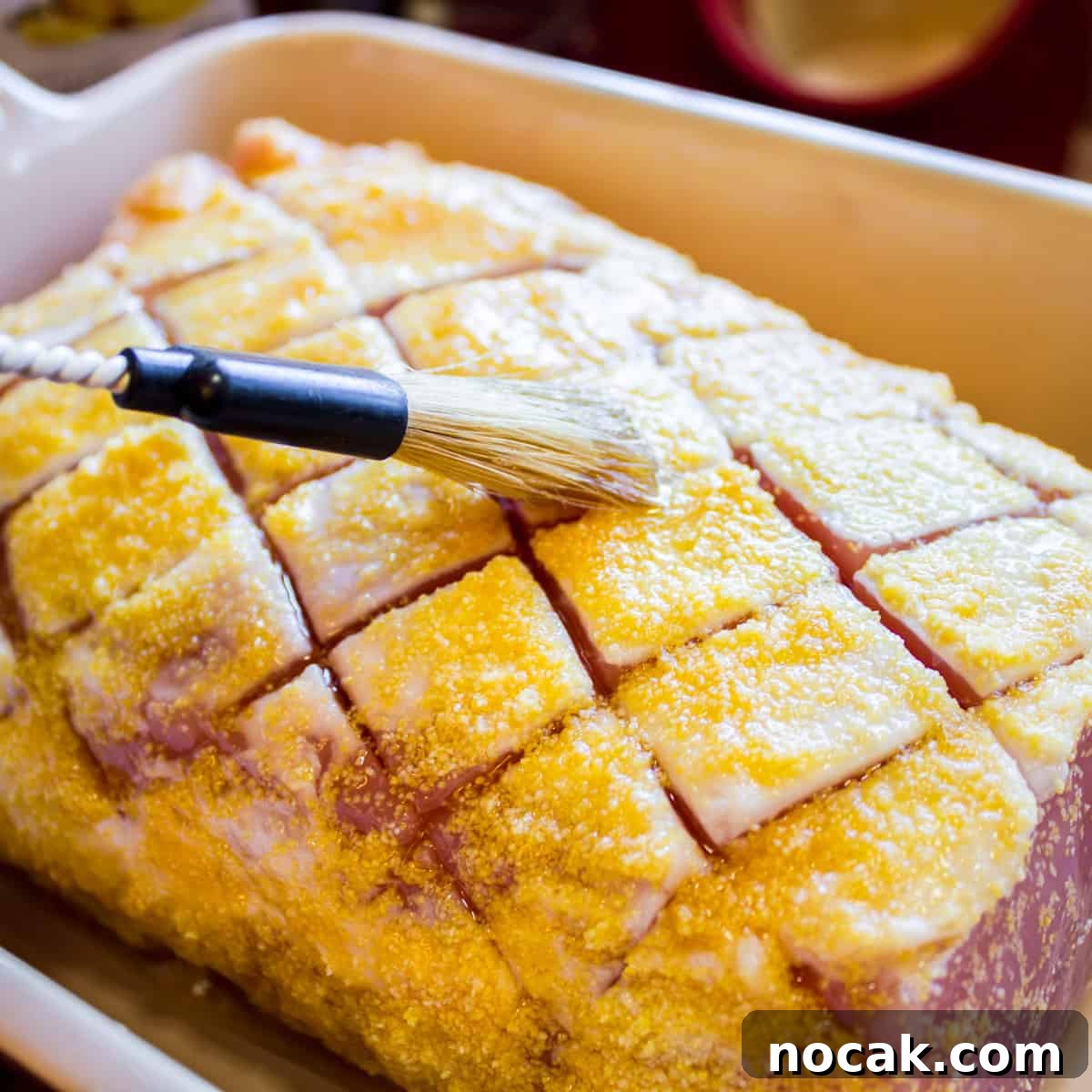 Brushing some maple syrup on an uncooked piece of meat.