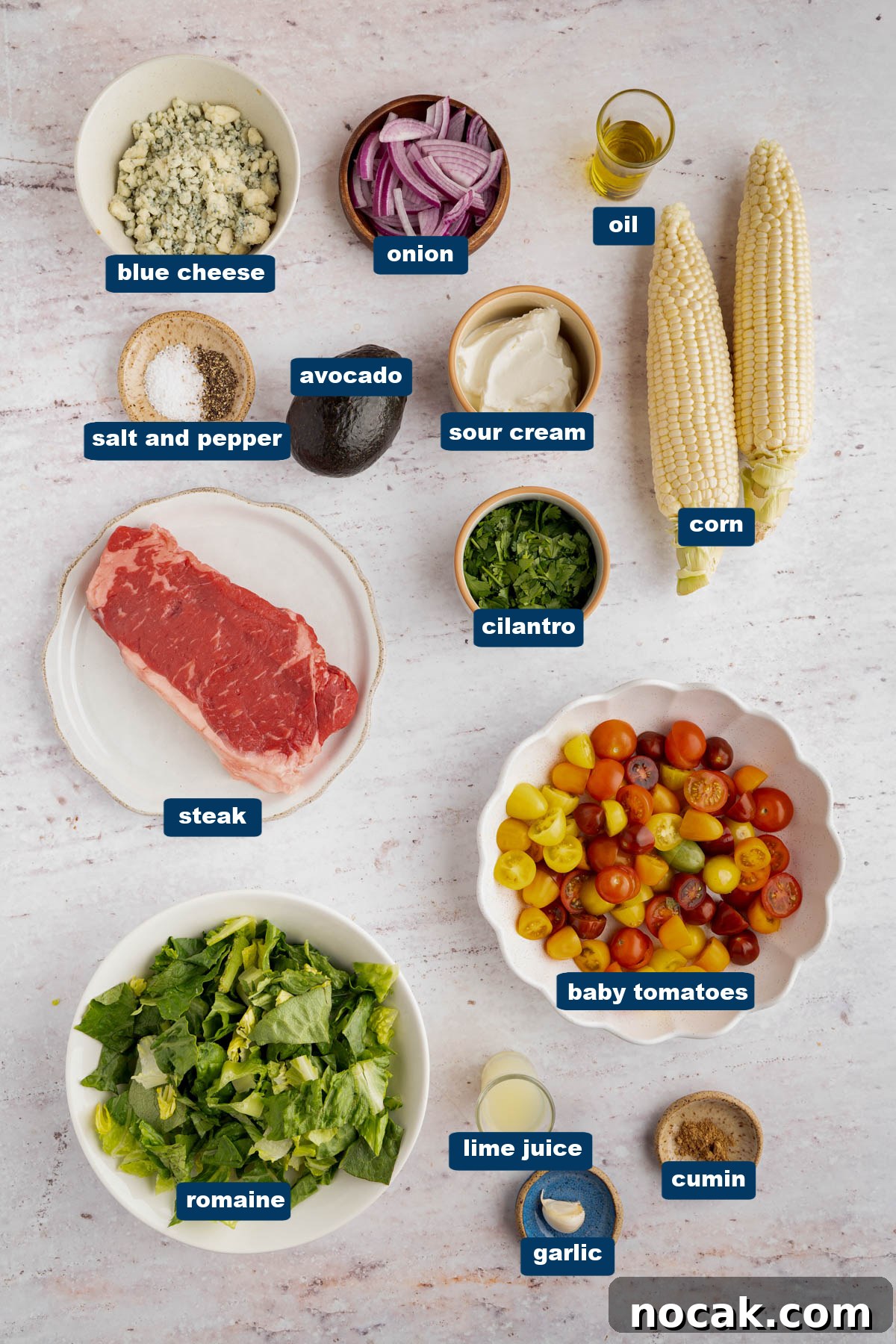 Steak Salad with Avocado-Lime Cilantro Crema Recipe 2 All of the ingredients for steak salad in bowls on a white countertop.