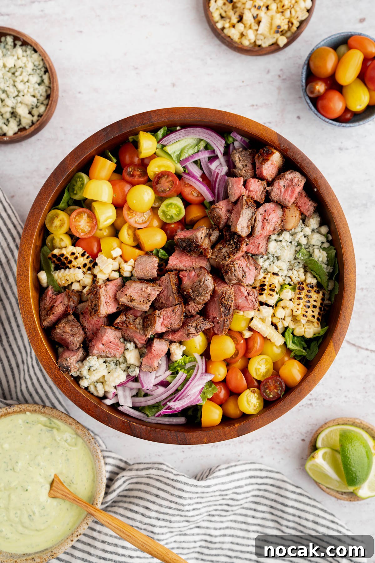 Steak Salad with Avocado-Lime Cilantro Crema Recipe 11 The finished steak salad in a bowl with the avocado lime crema off to the side.