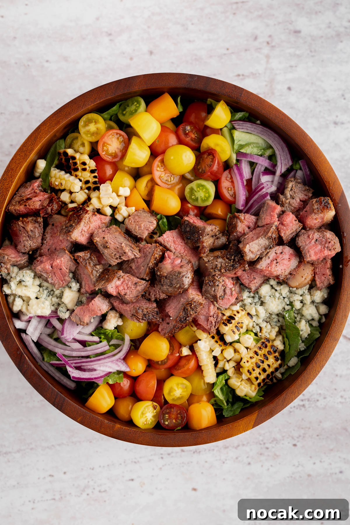 Steak Salad with Avocado-Lime Cilantro Crema Recipe 10 The fully assembled steak salad without the dressing in a bowl on a white countertop.