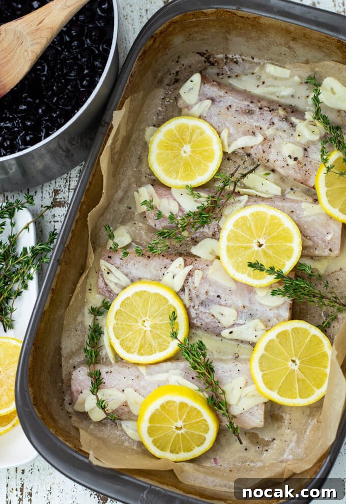 Oven-Baked Mahi Mahi with Blueberry Glaze 5 A casserole dish with uncooked mahi mahi and slices of lemon and fresh sprigs of thyme sit on the fish.