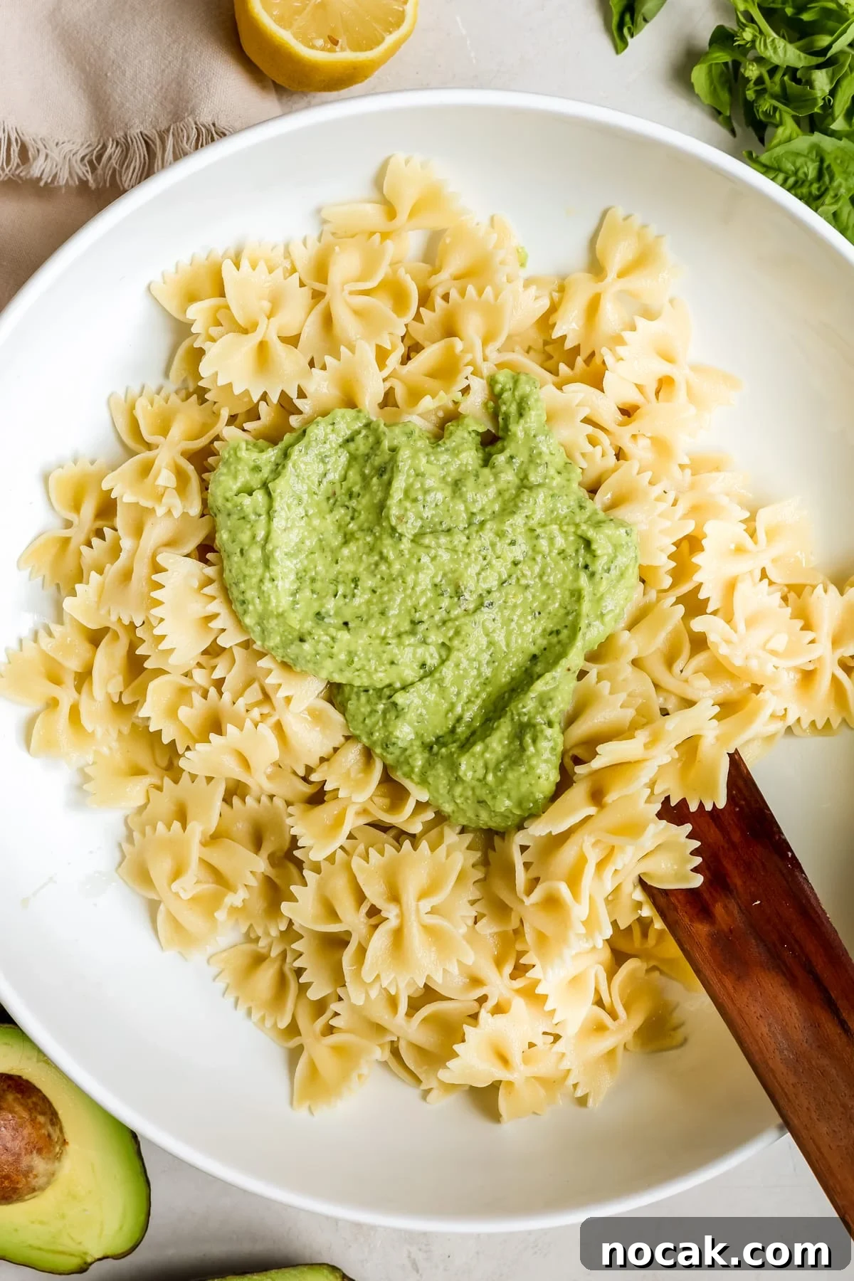 Creamy Avocado Pesto Pasta Recipe for Quick Weeknight Meals 6 pasta in a white bowl with pesto on top.