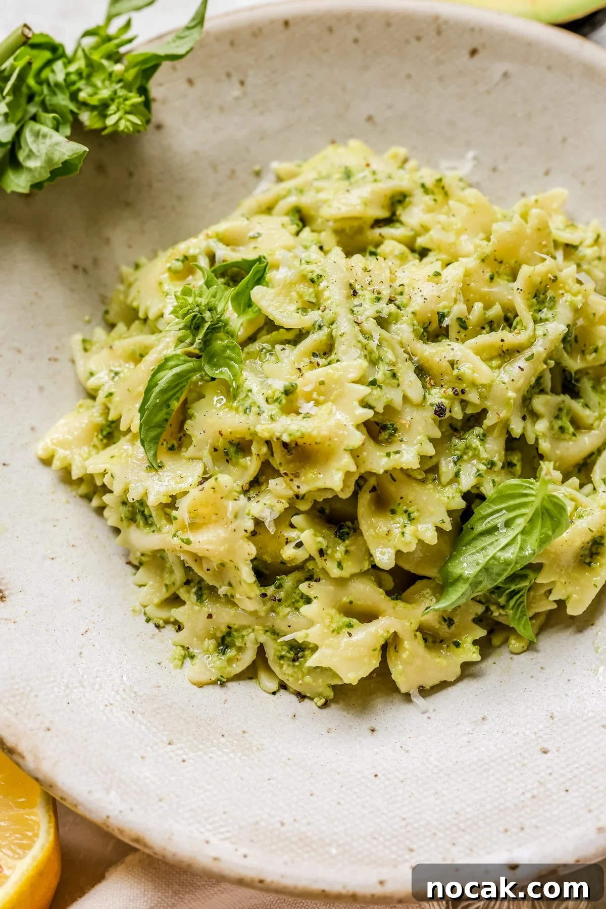 Creamy Avocado Pesto Pasta Recipe for Quick Weeknight Meals 8 pesto in a bowl garnished with basil and black pepper.