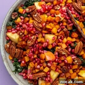 Harvest kale salad, in a grey bowl, sits on a purple background.