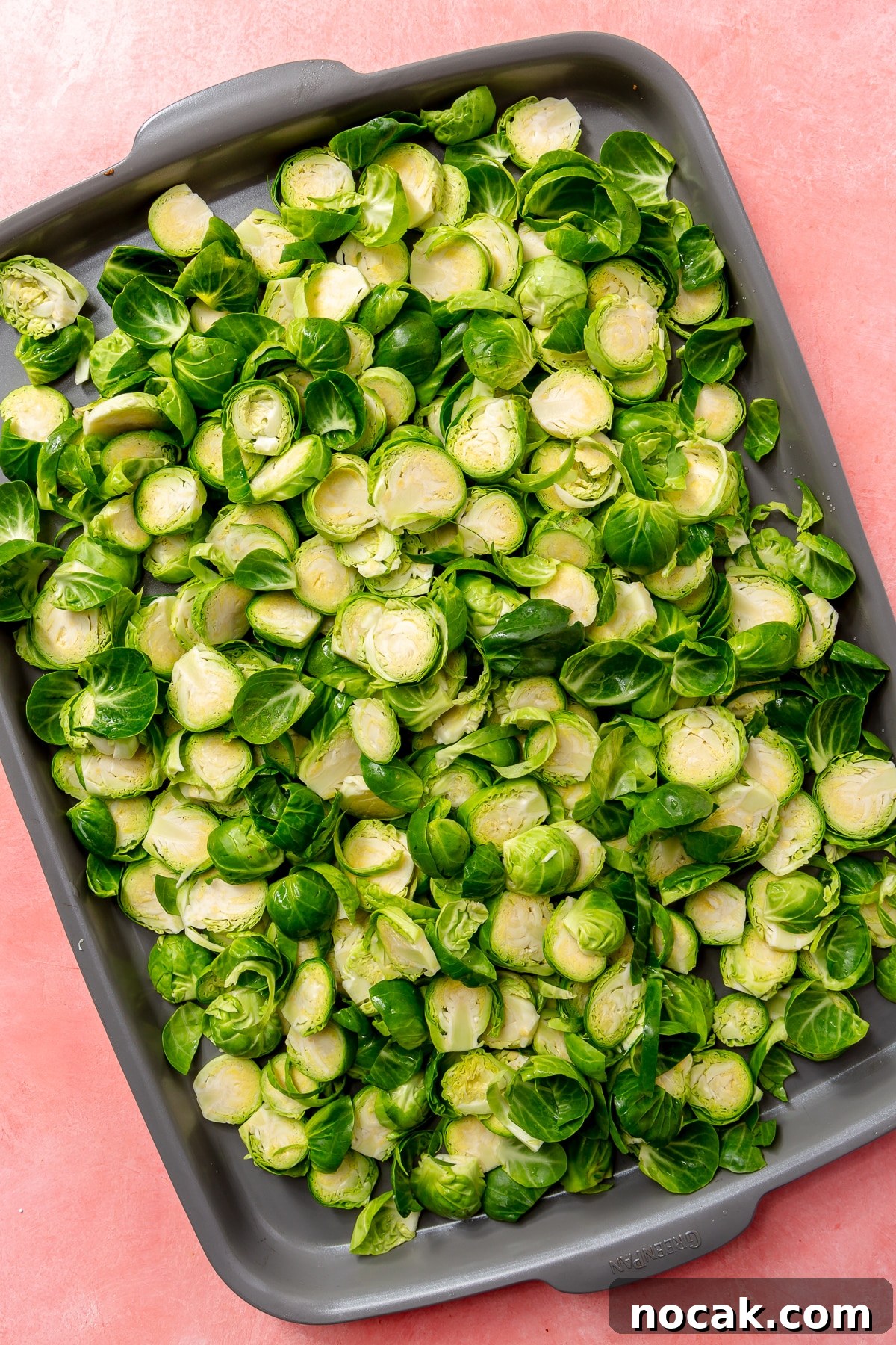 Roasted Brussels Sprouts and Pomegranate Salad with Citrus Vinaigrette 4 Halved brussels sprouts lay, in an even layer, on a grey baking tray.