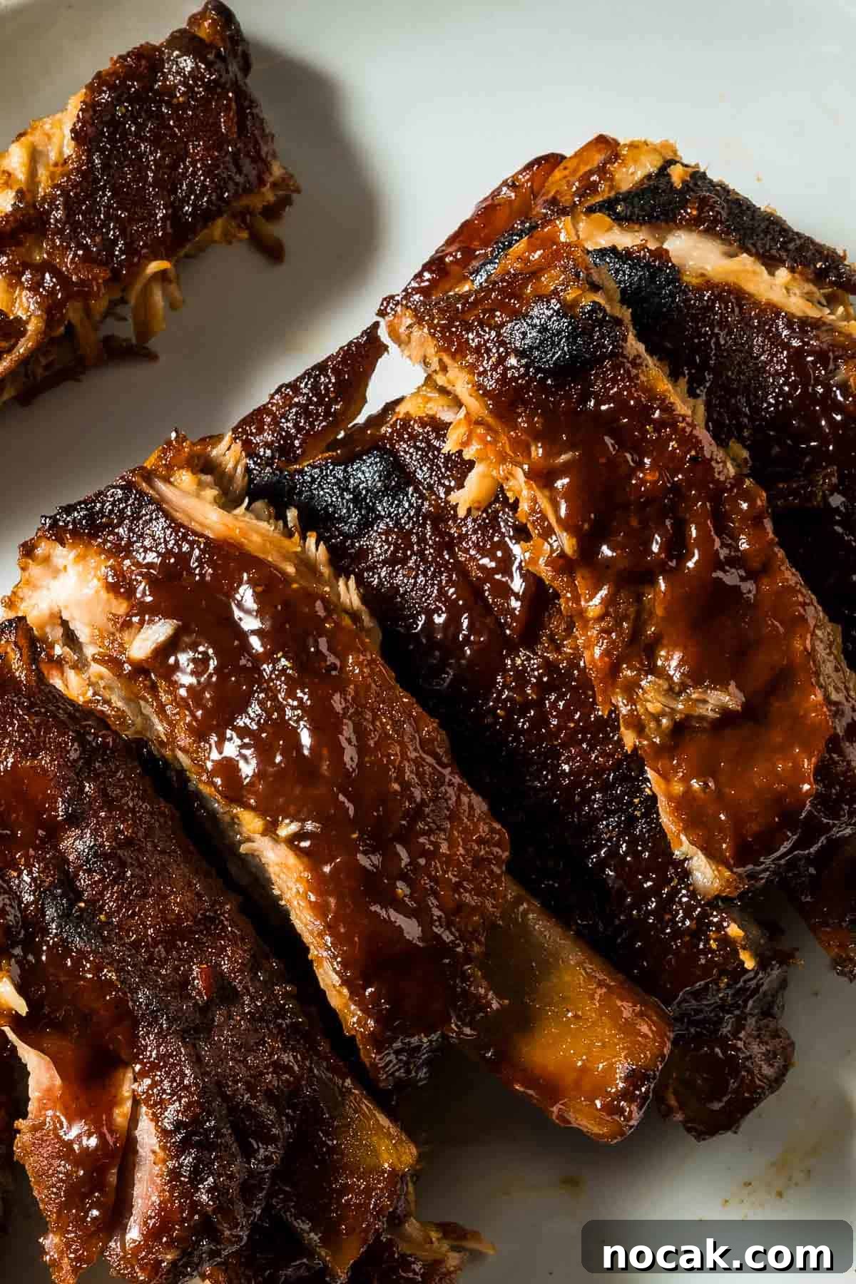 oven baked BBQ ribs with a rich, sticky glaze on a white plate, showcasing tender, flavorful meat perfect for barbecue lovers.