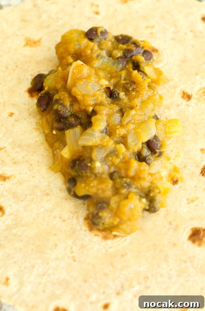 Adding the filling to the tortillas in the Butternut Squash Black Bean Enchilada Recipe
