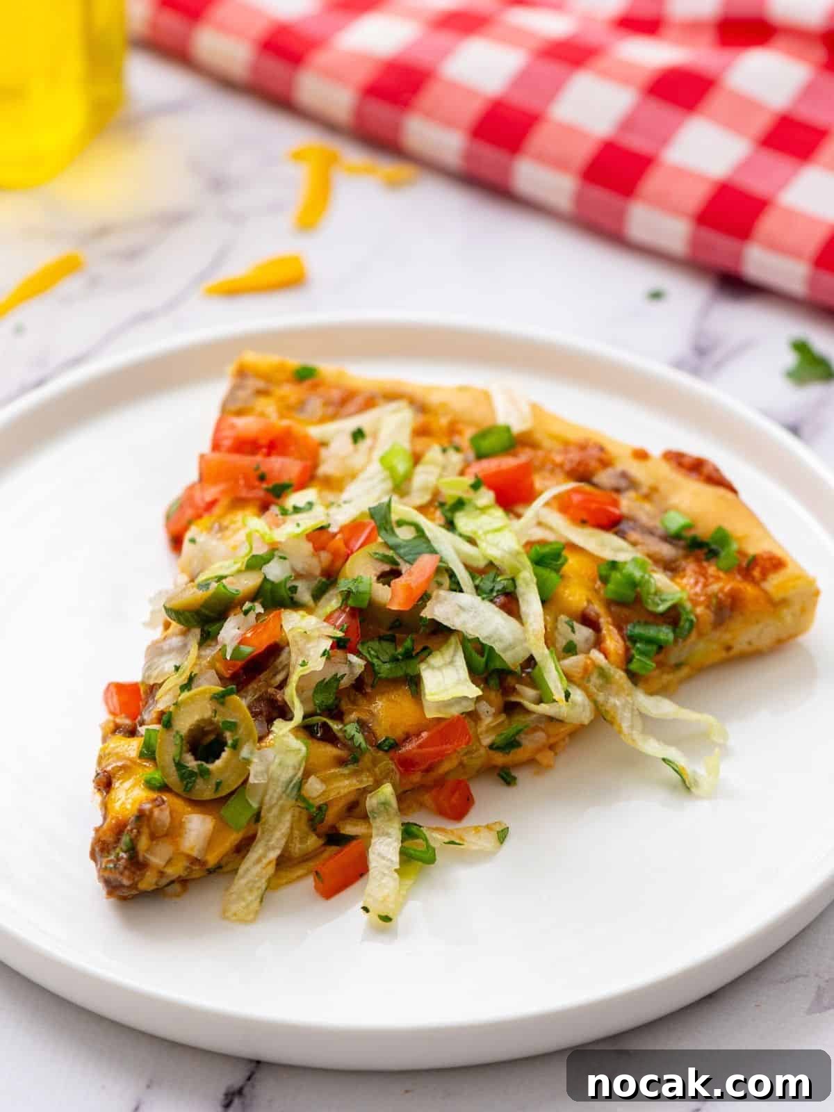 Taco Pizza Slice of taco pizza with toppings on white plate.