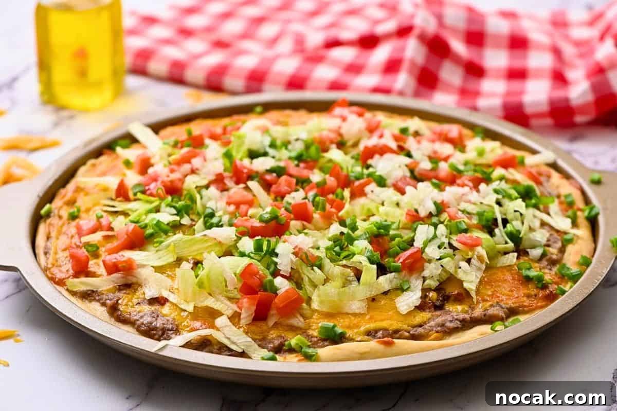 Copycat Taco Pizza Recipe Taco Pizza made with refried beans, salsa, taco meat, cheese and taco toppings on pizza tray.