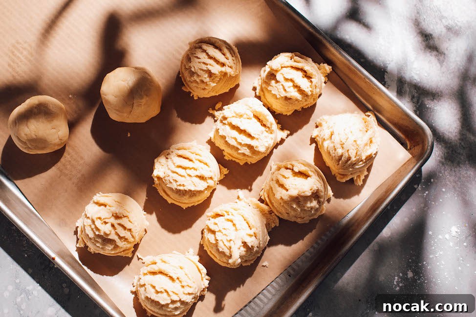 Soft Chewy Lemon Sugar Cookies Recipe for Perfect Texture 8 lemon sugar cookie dough scooped into balls on a cookie sheet with parchment paper.