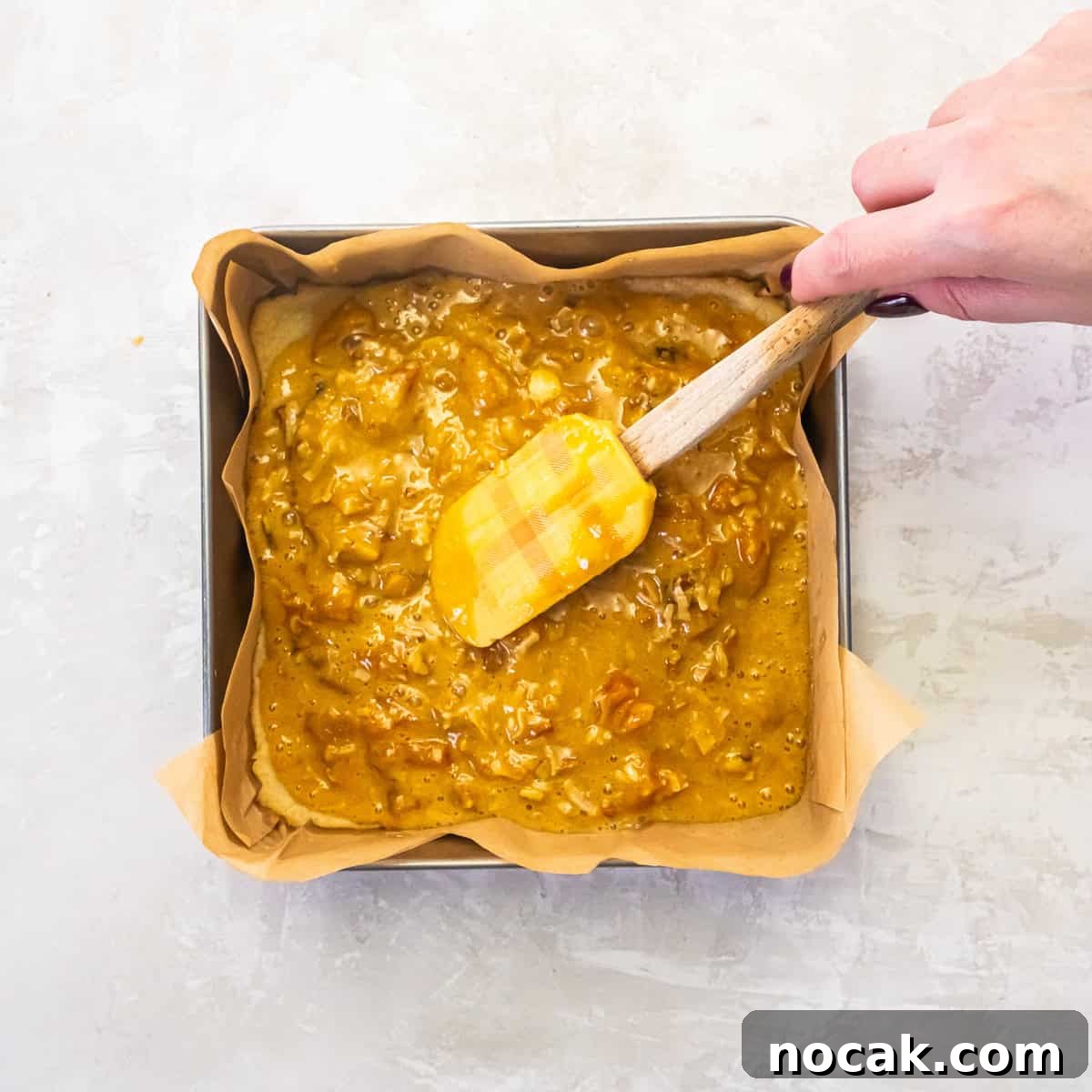 Chewy Apricot Bars with Oat Crust and Almond Glaze 12 Apricot bar topping being spread evenly over the baked crust in a square pan.