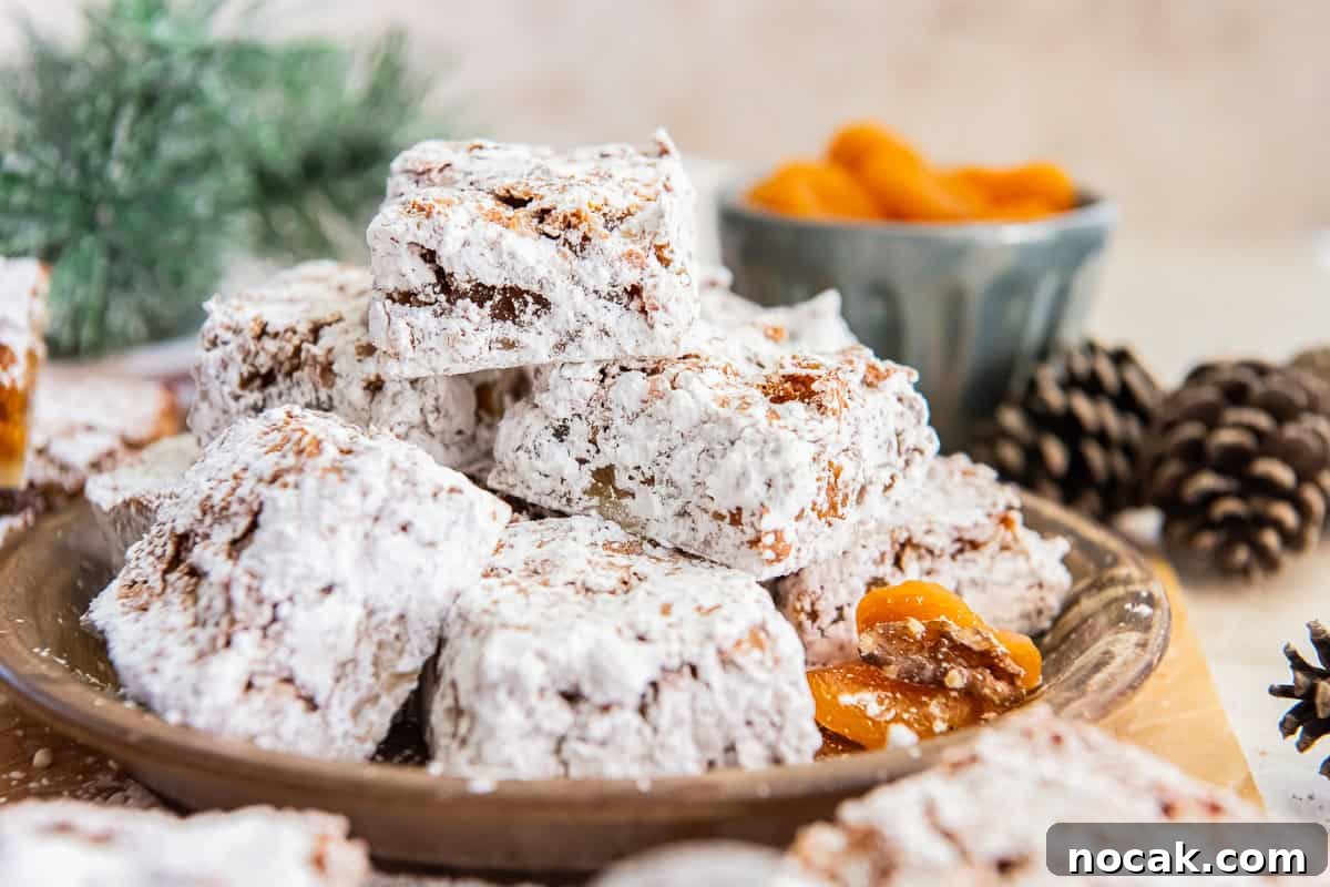 Chewy Apricot Bars with Oat Crust and Almond Glaze 13 Apricot bars dusted with powdered sugar, stacked on a rustic plate with dried apricots in the background.