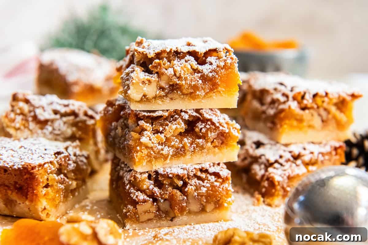 Chewy Apricot Bars with Oat Crust and Almond Glaze 5 Stacked apricot bars showing the shortbread crust and chunky apricot-walnut filling, dusted with powdered sugar.