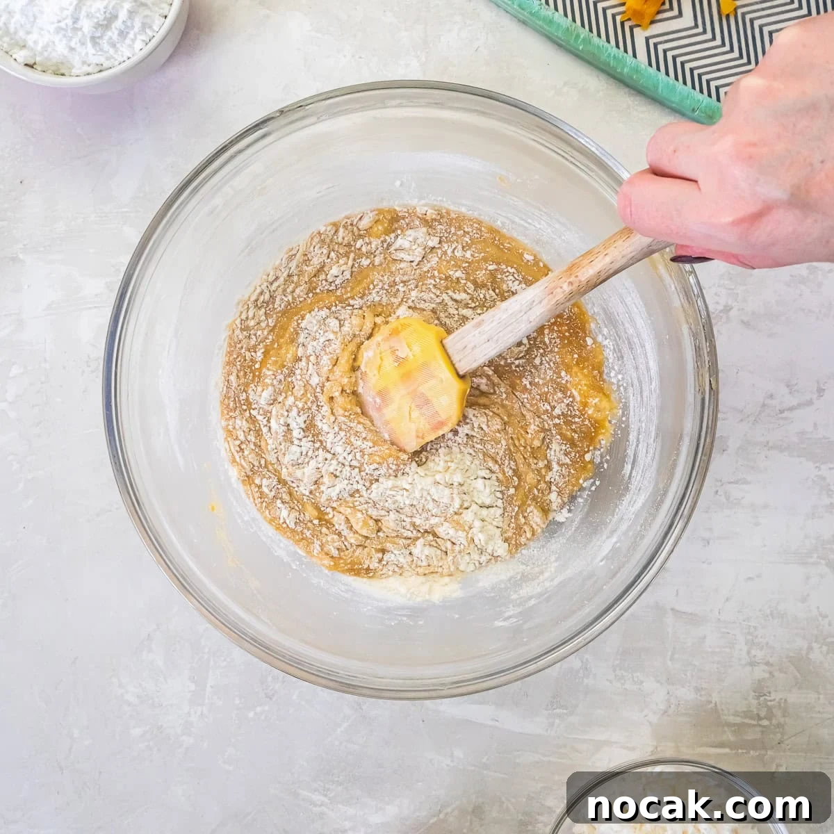 Chewy Apricot Bars with Oat Crust and Almond Glaze 10 Dry ingredients being folded into apricot bar batter with a spatula.