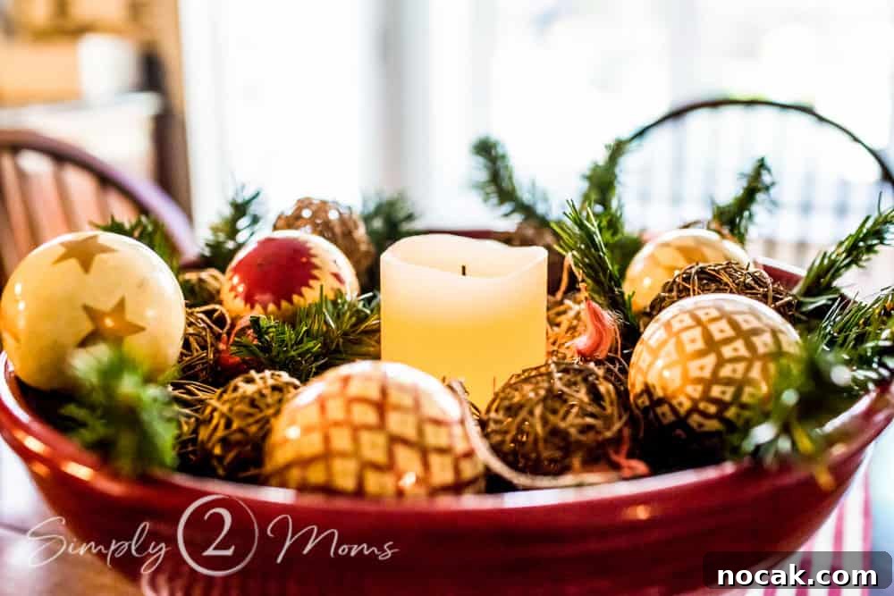 large bowl filled with greenery, Christmas ornaments, and a candle