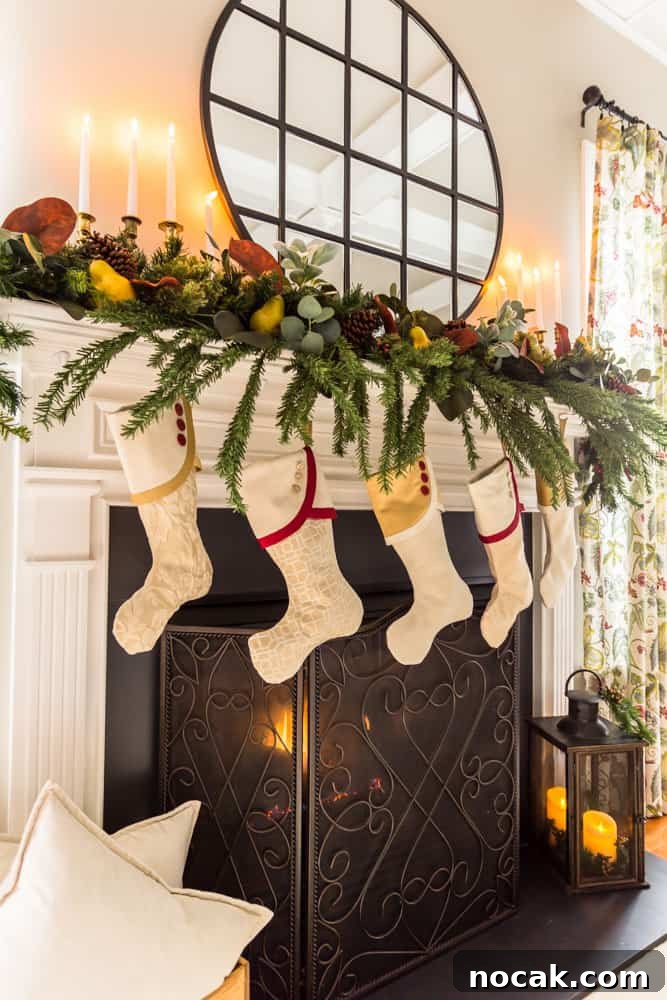 Five coordinating Christmas stockings hanging from a fireplace mantle decorated with greenery