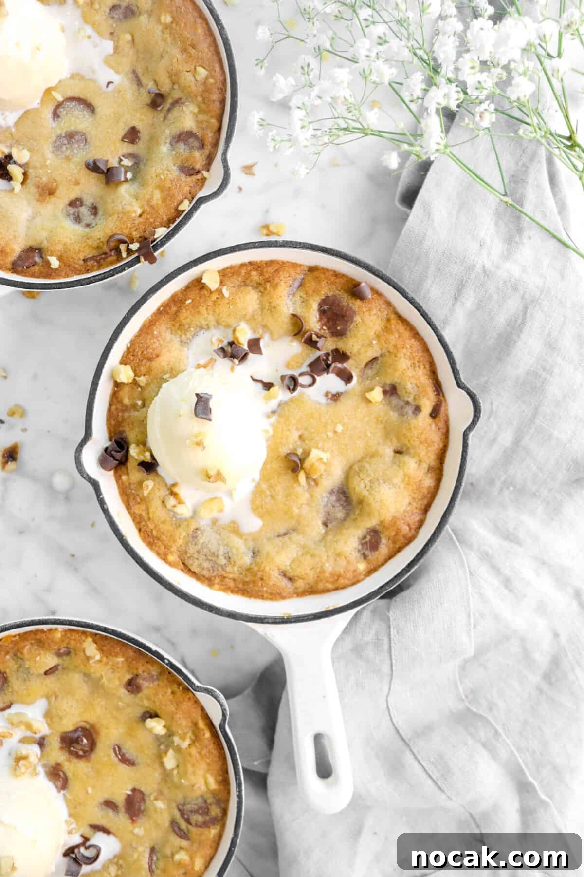 skillet cookie with a grey napkin, a scoop of ice cream, and flowers