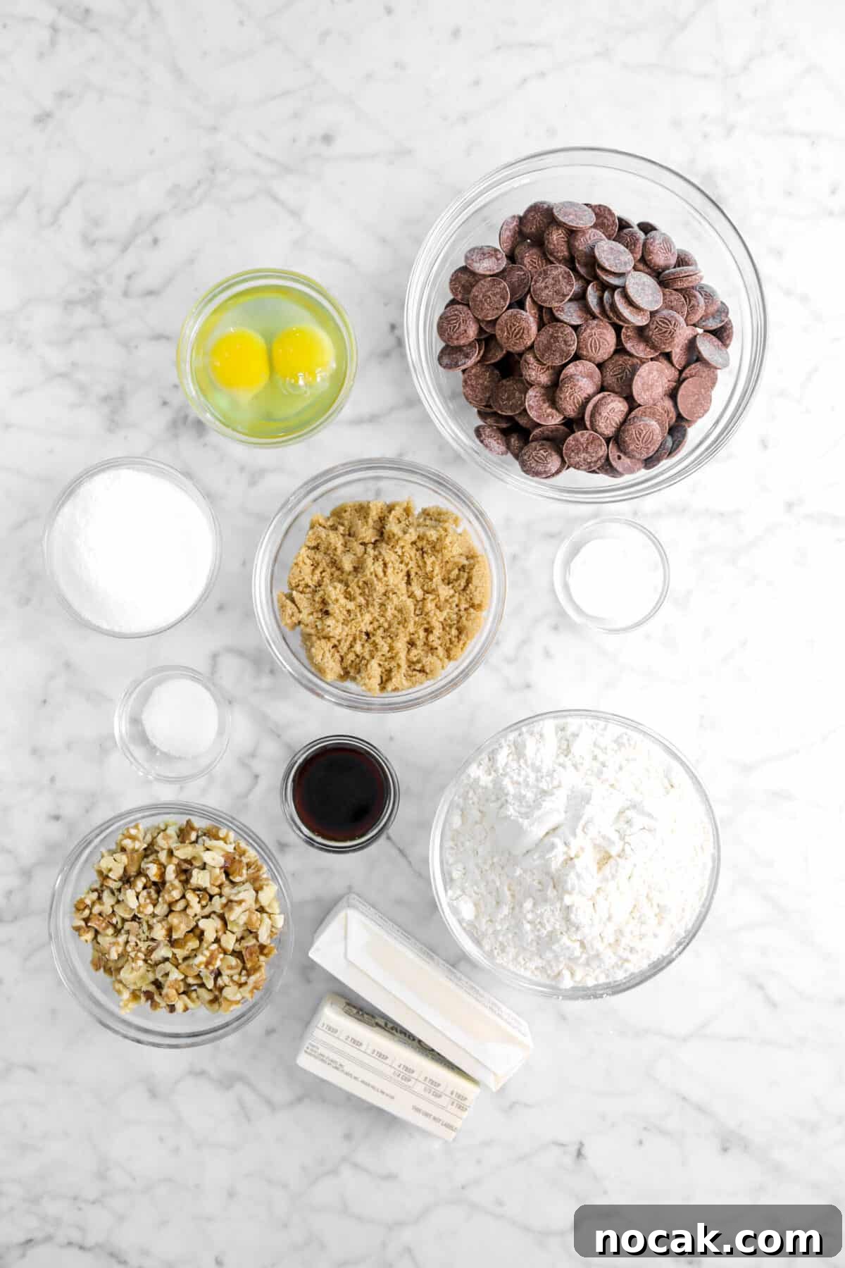chocolate chips, eggs, brown sugar, baking soda, sugar, salt, vanilla, flour, butter, and walnuts on marble counter