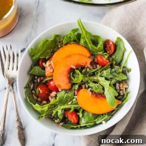 Arugula, Peach & Farro Salad with Orange Vinaigrette 11 Bowl of arugula peach salad next to two forks.