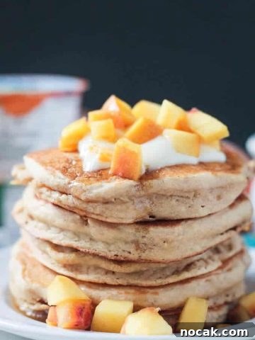 Close up photo of a stack of 5 peach pancakes.