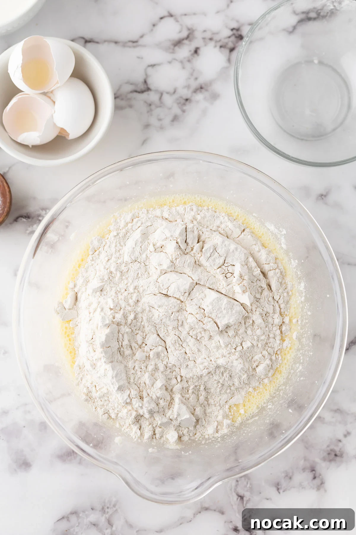 Creamy Banana Pudding Poke Cake Recipe for Dessert Fans 6 Flour, baking powder, and baking soda are added to the wet ingredients in the mixing bowl.